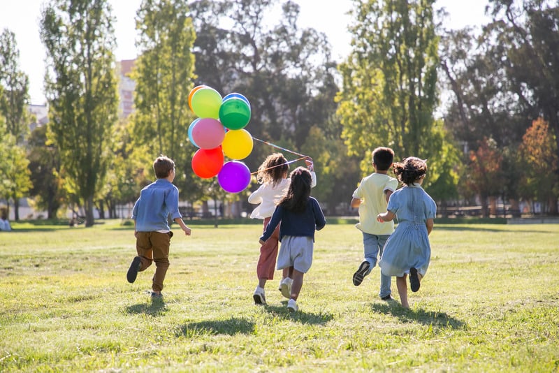 Children running in a park with balloons